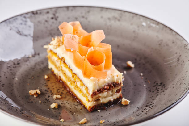 Piece of delicious carrot cake with egg white frosting served on white plate