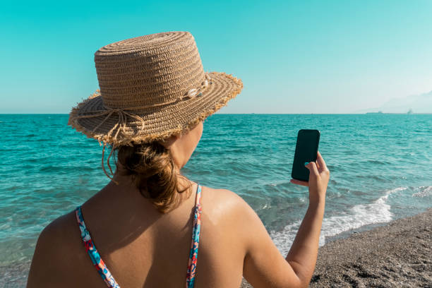 istock Woman on the beach spending time with her phone 1420445117