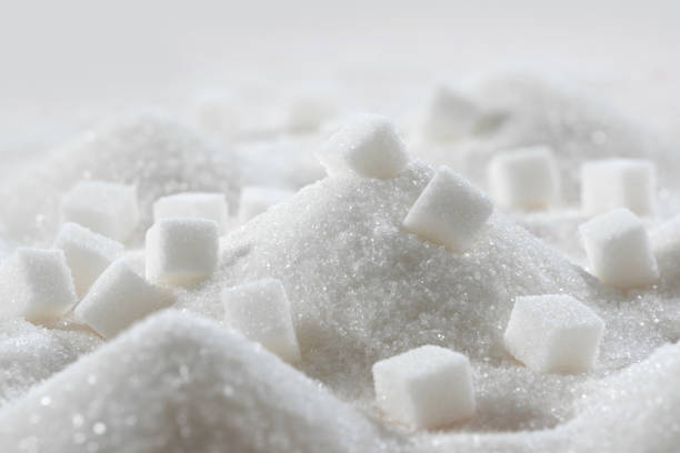 White granulated sugar and refined sugar cubes close-up in the kitchen White granulated sugar and refined sugar cubes close-up in the kitchen. sugar stock pictures, royalty-free photos & images