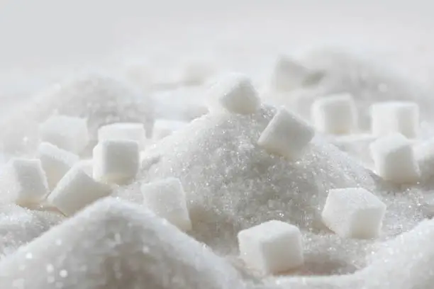 Photo of White granulated sugar and refined sugar cubes close-up in the kitchen