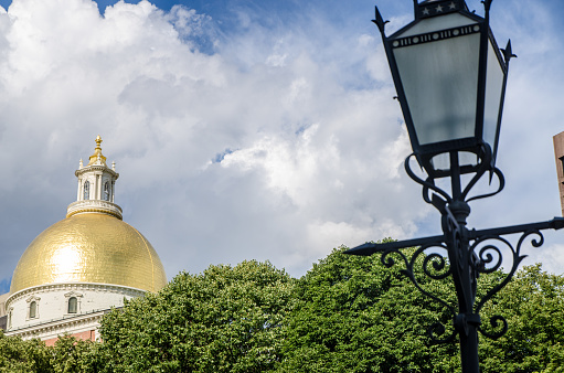 Golden dome of Boston State House during summer day with street light in foreground