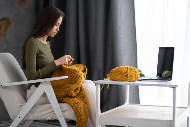 istock woman at home following a tutorial channel on laptop computer to learn knitting work wool activity for her hobbies or job. female knitting wool with internet class 1420458497