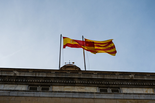 Flag of Spain and flag of Catalonia side by side in the wind in Barcelona