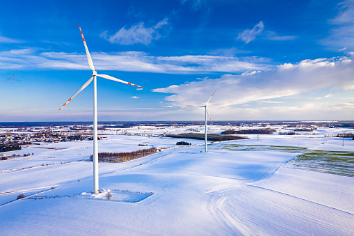Alternative energy at winter. Snowy field and wind turbine. Aerial view of nature in Poland, Europe