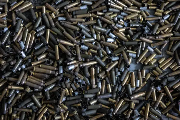 Photo of on the floor in the shooting range there are casings from fired cartridges of various calibers - from pistols, assault rifles, carbines, rifles