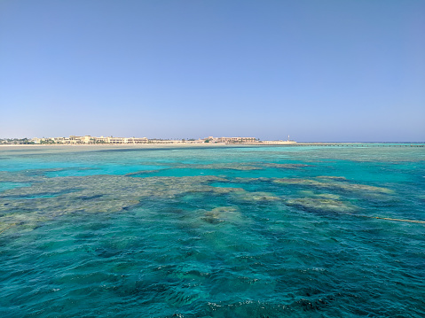 Beautiful view of the Red Sea with a coral reef against the backdrop of Egyptian hotels and blue skies. Hurghada, Egypt. Copy space.