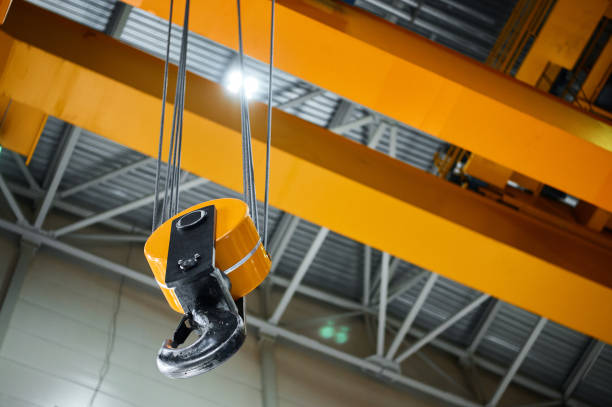 istock Hook assembly of yellow crane hangs under ceiling in shop 1420486781