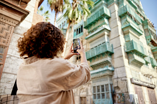 Joven turista en Jeddah fotografiando casas históricas photo