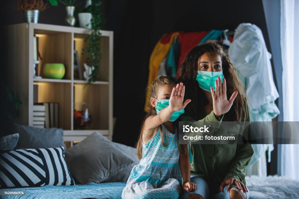 Don't come if you don't have a mask! Front view of mother and daughter asking someone not to approach them without wearing a protective mask to avoid virus infection. 25-29 Years Stock Photo