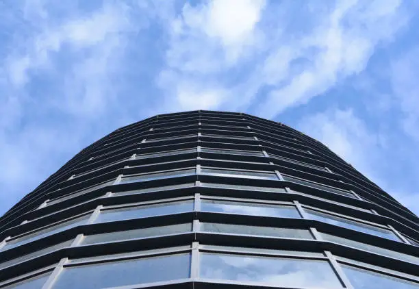 a modern building with a blue sky with clouds above it