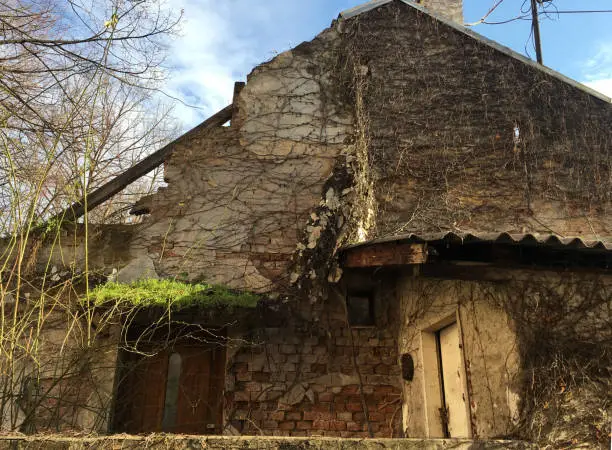 an abandoned and ruined house with a blue sky and white clouds