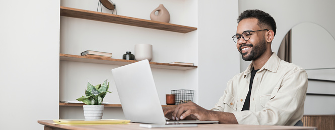 Hombre guapo usando computadora portátil trabajando en casa, reunión en línea, estudio a distancia photo