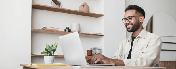 istock Handsome man using laptop working at home, online meeting, distance studying 1420488532