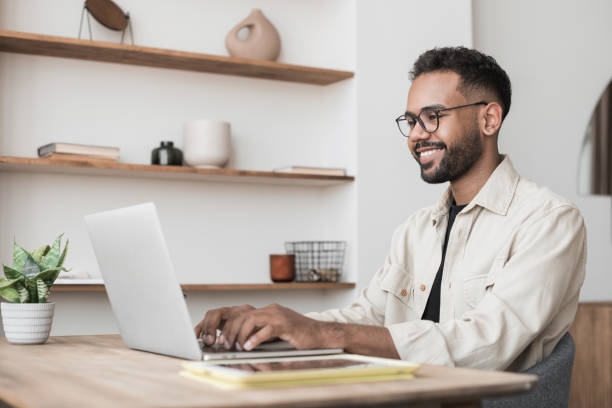 istock Cheerful man using laptop working at home, online meeting, distance studying 1420488543
