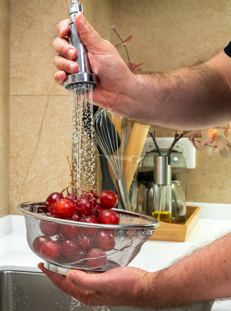 istock A man washes table grapes under a strong spray of water 1420489328