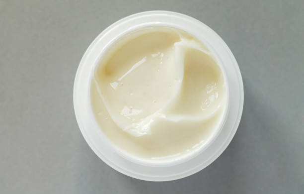Cream for face and body care in open canister, on a black background