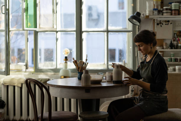 istock Young skilled lady concentrated on modeling jug from raw clay enjoys hobby creating vase 1420491308