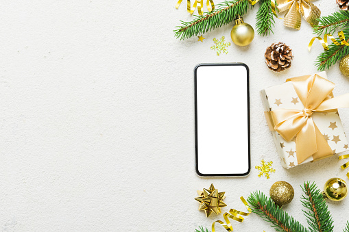 Digital phone mock up with rustic Christmas decorations for app presentation top view with empty space for you design. Christmas online shopping concept. Tablet with copy space on colored background.