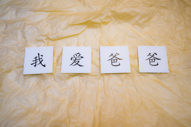 A man's hand is writing Chinese calligraphy on a piece of red paper for Chinese New Year greetings