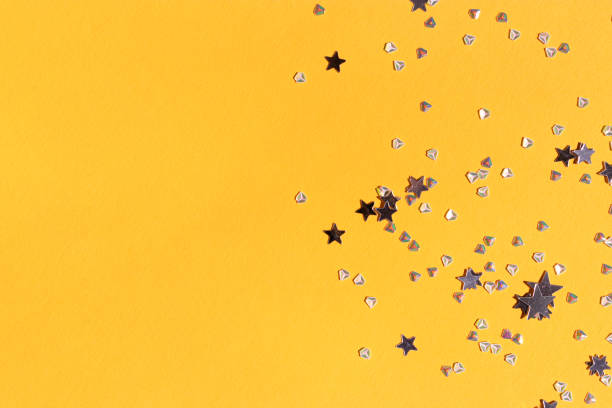 istock Shiny silver stars and crystals confetti on a yellow background. 1420495654