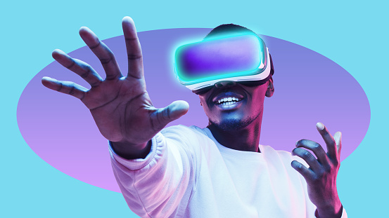 African man wearing VR headset exploring metaverse world, touching virtual reality subjects in online ar game