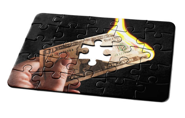 istock Jigsaw puzzle depicting a burning US $10 banknote, with one missing piece, representing a problem to be solved 1420497902