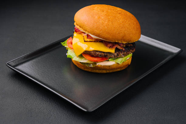 istock Close up tall tasty burger with cheese served on tray 1420505651