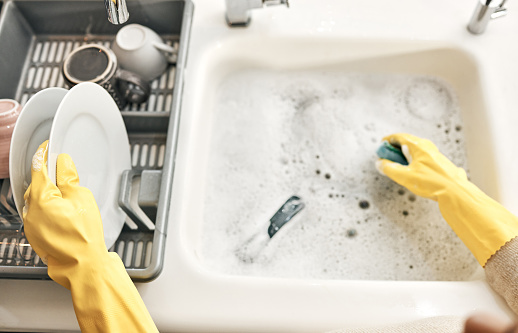 Housewife, maid or cleaner hands washing dishes in the kitchen sink for home hygiene, wearing rubber gloves. Contact us for cleaning solutions or professional domestic household chores service.