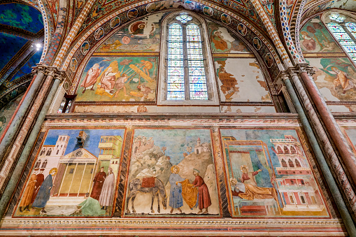 The magnificent frescoes by Giotto inside the Basilica di San Francesco (Basilica of Saint Francis), in the medieval heart of Assisi, in Umbria. Built in the Italian Gothic style starting from 1228 and completed in 1253, the Basilica preserves the mortal remains of the Saint of the Poor from 1230. In the image, some of the 28 walls frescoed by Giotto between 1292 and 1305, illustrating the life of the Saint of Assisi, from his vocation to death. Over the centuries Assisi and the spirituality of these places have become a world reference point for peace, tolerance and solidarity between all the peoples and different confessions. The Umbria region, considered the green lung of Italy for its wooded mountains, is characterized by a perfect integration between nature and the presence of man, in a context of environmental sustainability and healthy life. In addition to its immense artistic and historical heritage, Umbria is famous for its food and wine production and for the quality of the olive oil produced in these lands. Since 2000 the Basilica and other Franciscan sites of Assisi have been declared a World Heritage Site by UNESCO. Super wide angle image in high definition format.