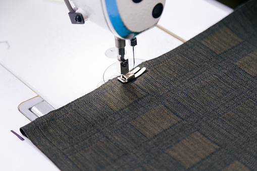 Close up of tailor working on electric sewing machine