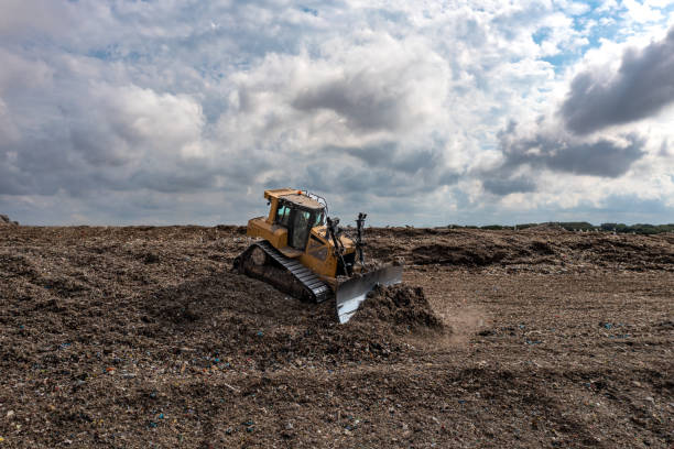 Bulldozer moving waste on a landfill site A Bulldozer machine moving waste and household garbage on a large landfill heap overflowing trash dumpster stock pictures, royalty-free photos & images