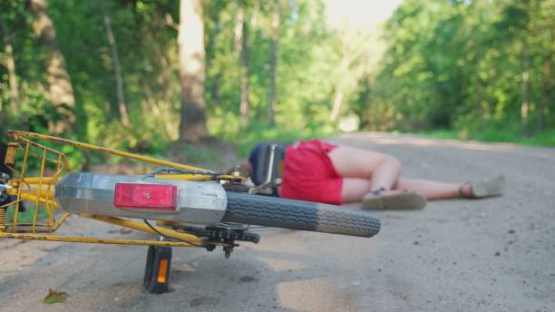 une jeune cycliste caucasienne inconsciente blessée allongée sur une route rurale après avoir été heurtée par une voiture - child bicycle cycling danger photos et images de collection