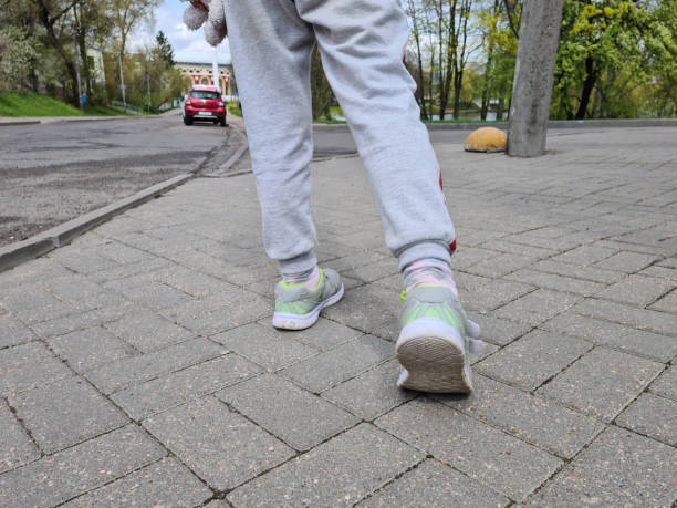istock Children feet in sneakers makes step along road 1420521632