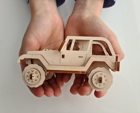 Wooden car in children hand protection safety and insurance. Ecological toys for children concept