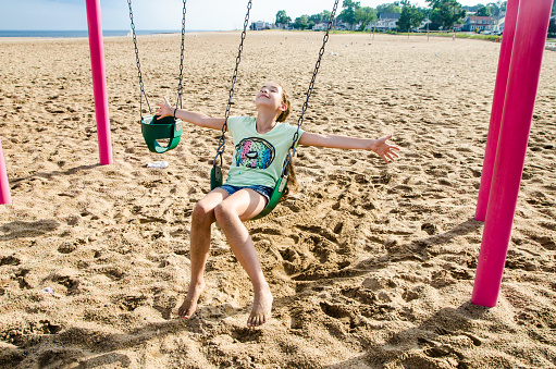 Cute little children having fun on a swing together in beautiful summer day on the beach . Active summer leisure for kids.
