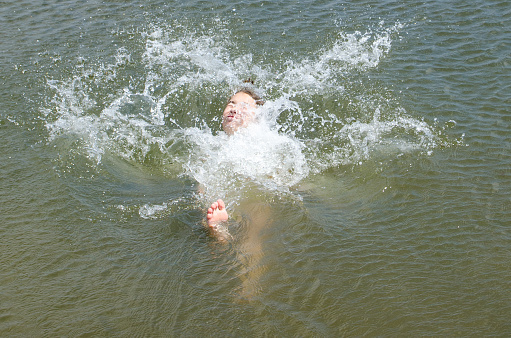 Teenage girl letting herself fall in water on her back during summer day vacation