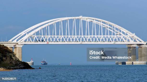 Breathtaking Seascape With A White Beautiful Bridge With Many Moving Cars Above The Water Surface And Sailing Ships Time Lapse Effect Shot Calm Sea With Ripples Huge Bridge Vessel And Bue Sky Stock Photo - Download Image Now