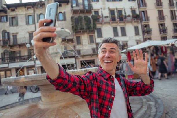 istock Man in a plaid shirt making selfie on a fountain background 1420534066