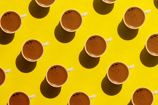 Pattern made of cup of coffee on yellow background