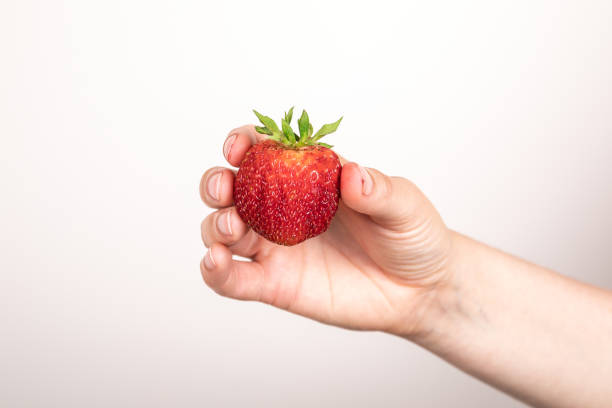 istock Red strawberry in hand on white background. Summer delicacy and vitamins 1420549089