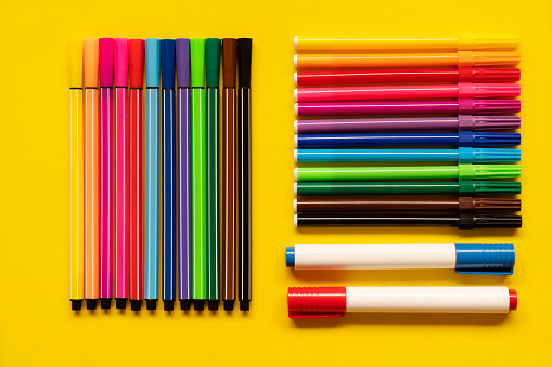 LONG WOODEN PENCILS OF VARIOUS COLORS, ON LIGHT WOODEN TABLE. HORIZONTAL PHOTOGRAPHY. COLOR.