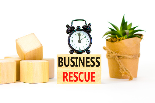 Business rescue symbol. Concept words Business rescue on wooden blocks on a beautiful white table white background. Black alarm clock. Business rescue and support concept. Copy space.