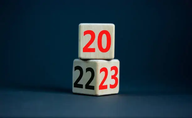 Photo of 2023 happy new year symbol. Wooden cubes symbolize the change from 2022 to the new year 2023. Beautiful grey table grey background. Copy space. Business and 2023 happy new year concept.