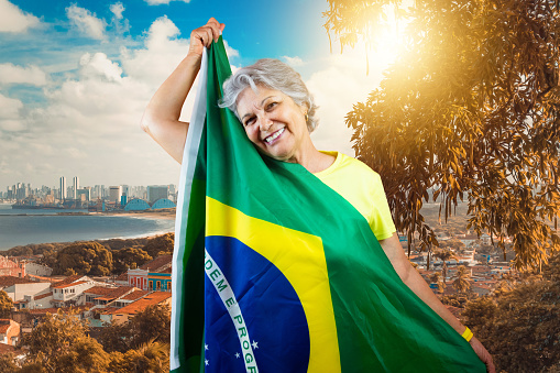Mature Woman with Gray Hair Holding Brazil Flag on Cinematic Background