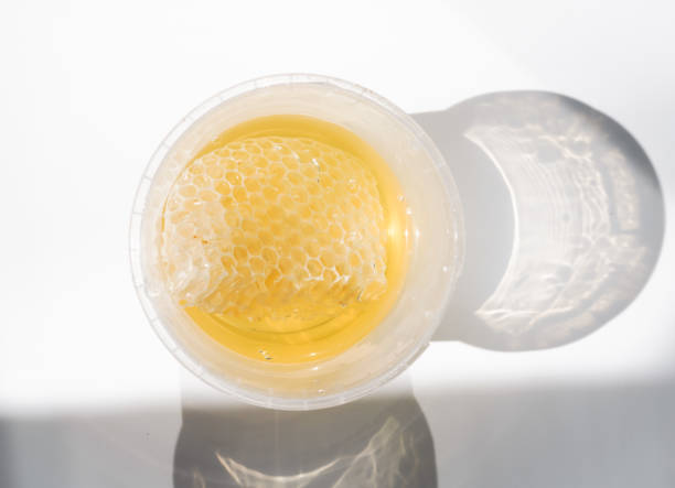 istock Honeycombs with transparent fresh honey in a plastic container on a white background 1420563278