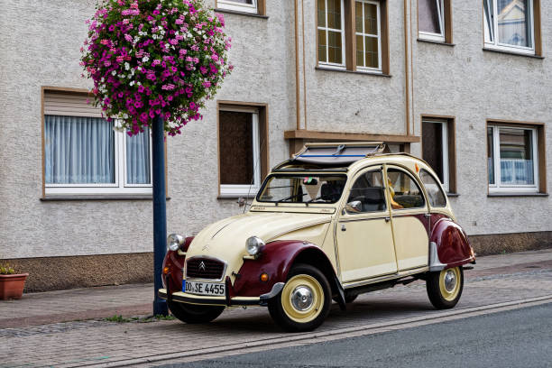 вид сбоку на винтажный автомобиль citroen 2cv ente бежевого цвета, припаркованный на улице - citroën 2cv стоковые фото и изображения