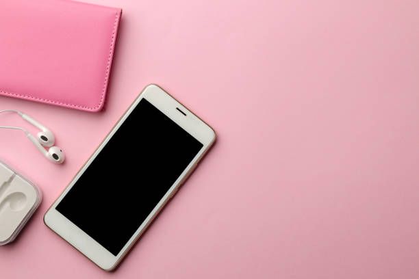 istock White smartphone and headphones and notepad on a bright pink background. view from above 1420572344