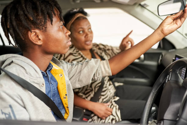 adolescent africain apprenant à conduire une voiture avec sa mère - africa south africa child african culture photos et images de collection