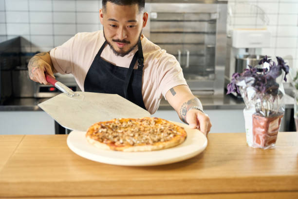 istock Proud young chef serving a freshly-baked tasty pizza 1420573012