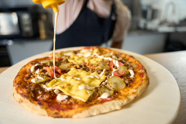 istock Dedicated chef adding delicious sauce to the frehsly-made pizza 1420573038